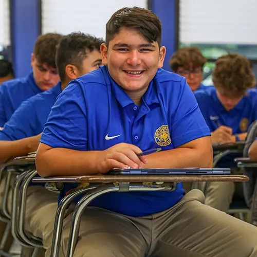 Students sitting at a desk smiling