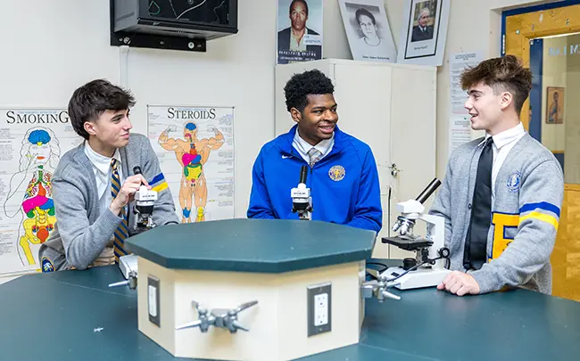 853A4721 3 boys standing with microscopes in front of them talking